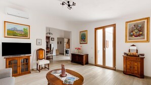 Un salón amplio con televisor de pantalla plana, muebles de madera y obras de arte en las paredes.