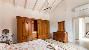 Un dormitorio con una cama grande, un armario de madera, una cómoda y un espejo.
