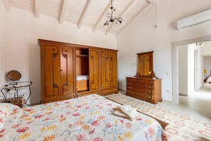 A bedroom with a large bed, wooden wardrobe, dresser, and a mirror. - Villa with garden and air conditioning (La Muddizza SS)