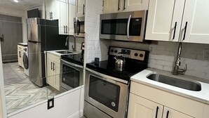 Una cocina moderna con electrodomésticos de acero inoxidable, armarios blancos y un suelo con patrón de espiga.