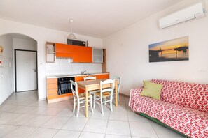 A compact living space with a kitchen, dining area, and a sofa. - Terrazza vista mare, Posteggio, Arie dir (Castelsardo)