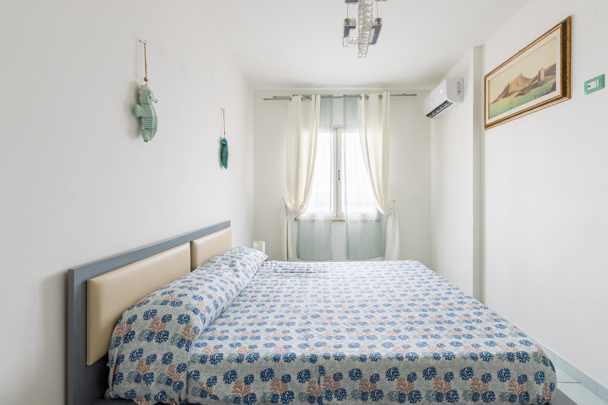 Een slaapkamer met een bed, een decoratie, een raam met gordijnen en een wandairconditioner.