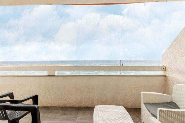 A balcony with a view of the beach and ocean.