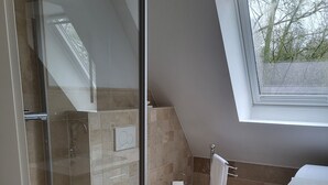 A modern bathroom with a glass shower enclosure, a toilet, and a sink. - Welcome to our Gala vacation apartment (Stade)