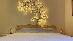Une chambre à coucher avec un lit, une tête de lit en bois et un luminaire mural conçu pour ressembler à un arbre.