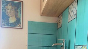 A kitchen with teal cabinets, a sink, and a cutting board with vegetables. - Mini Apartment in a Farm House on the High Hills Near Gubbio (Gubbio)