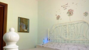 A bedroom with a bed, a wall-mounted artwork, and a decorative wall with text and dandelion illustrations. - Mini Apartment in a Farm House on the High Hills Near Gubbio (Gubbio)