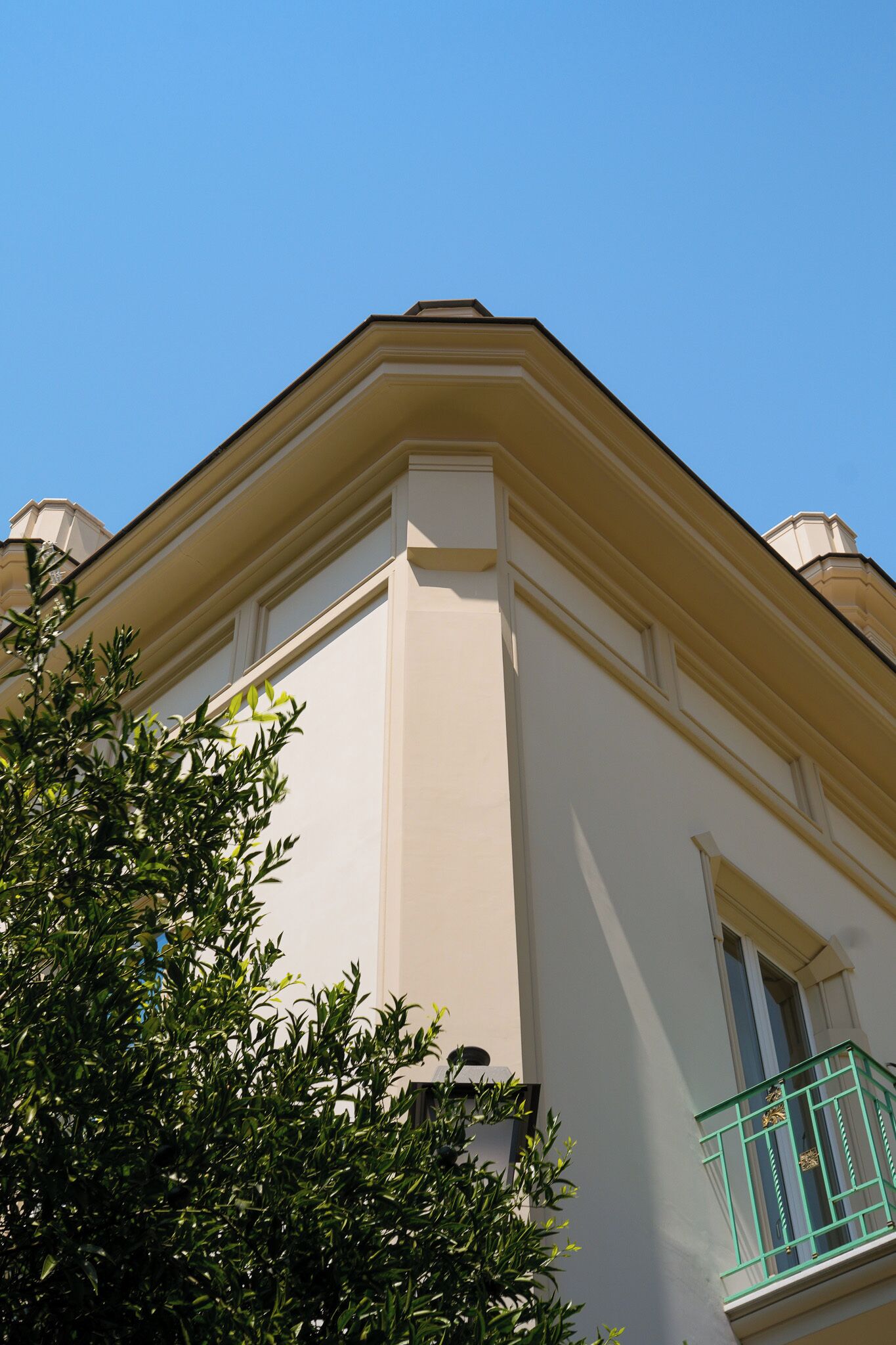 Un angolo di un edificio con facciata bianca e ringhiera del balcone verde.