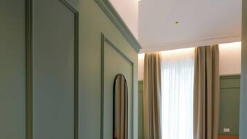Ein Hotelzimmer mit Bett, Schreibtisch, Stuhl, Spiegel und einem Fenster mit Vorhängen.