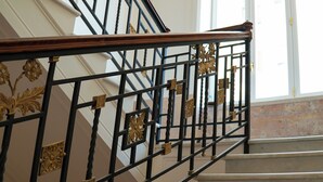 A staircase with ornate black metal railings and a wooden handrail. - Villa Liberty (Castellammare di Stabia)