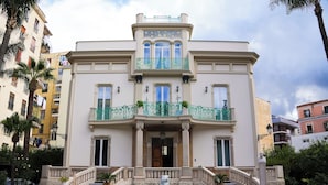 A multi-story building with a central entrance, a fountain, and a staircase leading to the entrance. - Villa Liberty (Castellammare di Stabia)