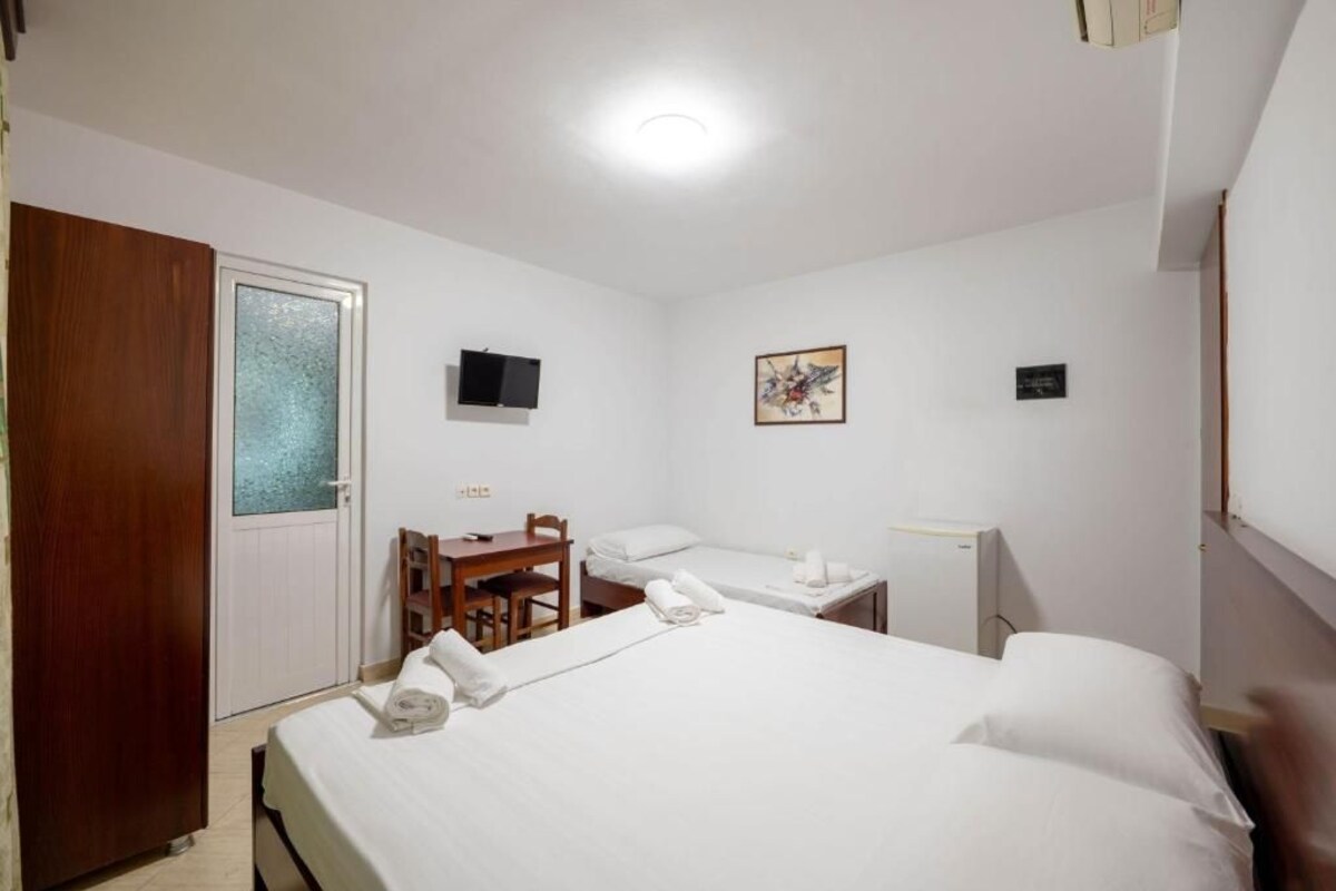 A hotel room with a bed, a desk, a chair, a television, and a door.