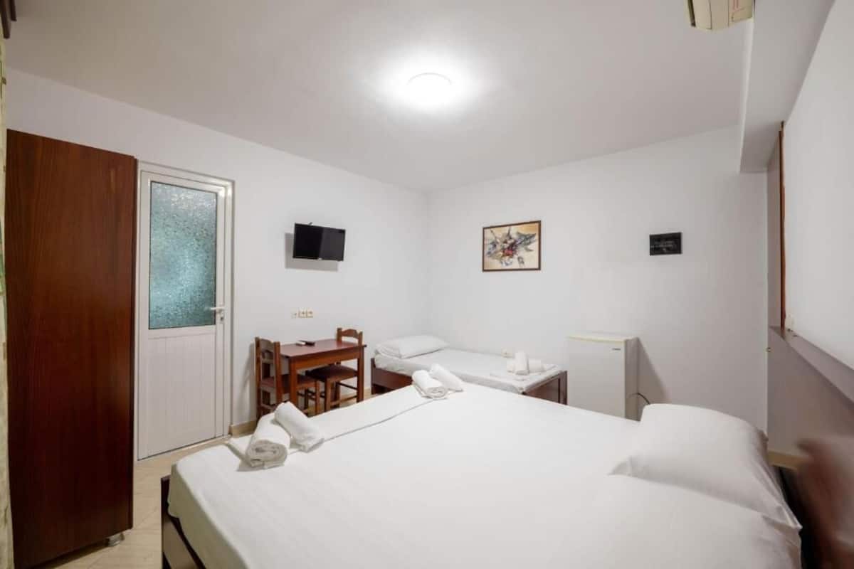 A hotel room with a bed, a desk, a chair, a television, and a door.