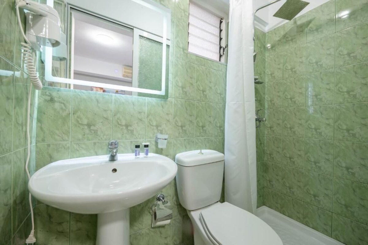 A bathroom with a white sink, toilet, and shower.