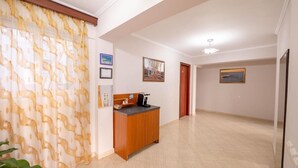 A spacious hallway with a wooden cabinet, a coffee machine, and framed pictures on the walls. - Hotel Venera (Sarande)