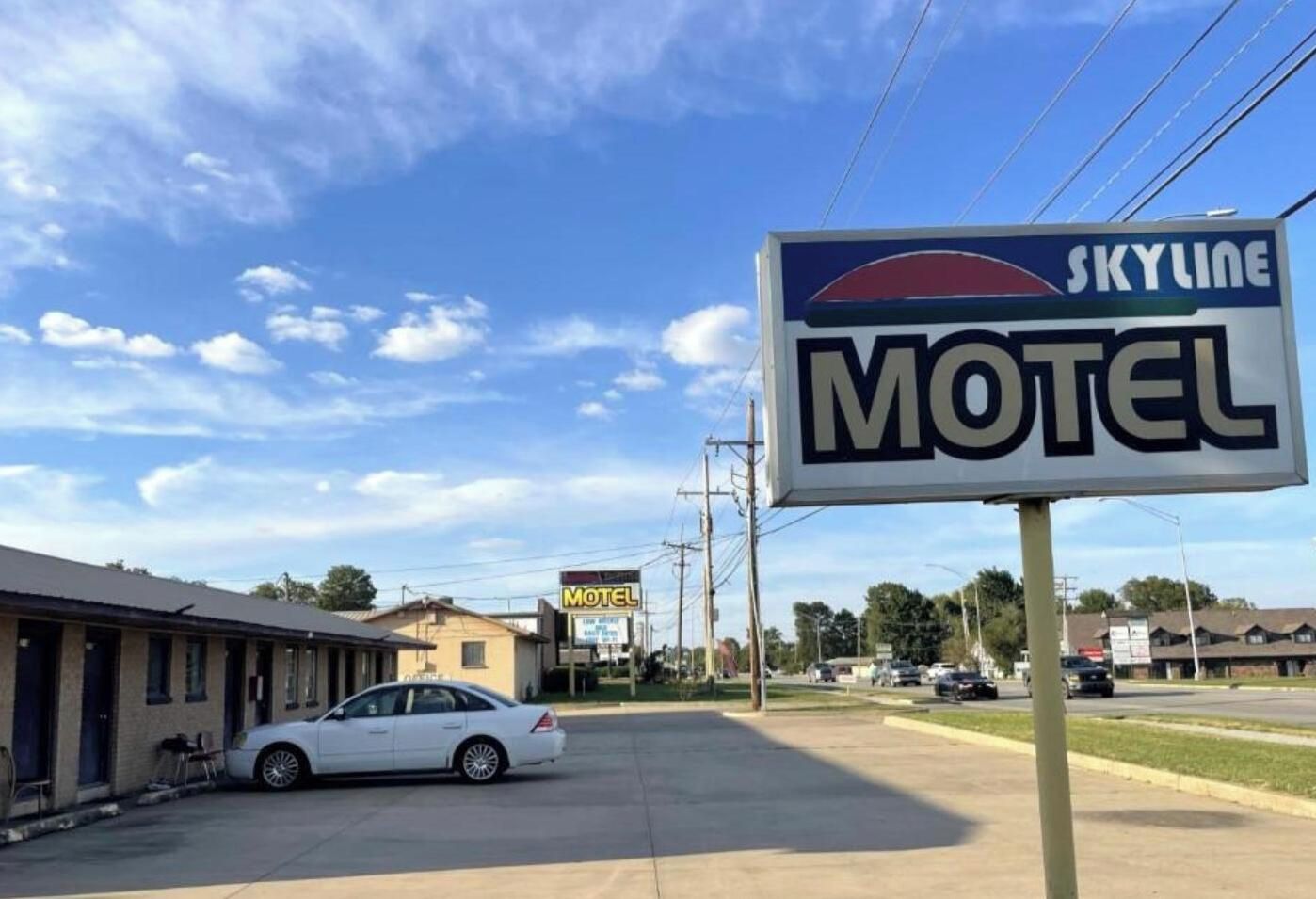 A motel with a clear sky and a parked car in front.