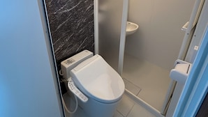 A modern bathroom with a marble wall, a toilet, and a shower area.