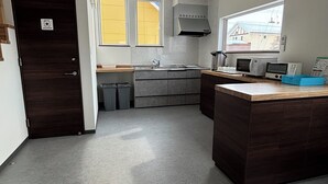 A modern kitchen with grey cabinets, a central island, a built-in microwave, and a window providing natural light.