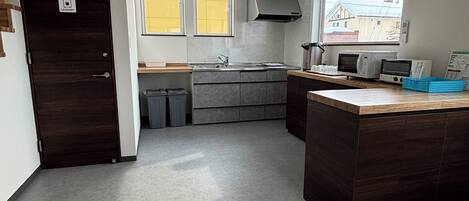 A modern kitchen with grey cabinets, a central island, a built-in microwave, and a window providing natural light.