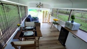 A compact kitchen with a dining area, featuring a table set for two, a microwave, and a small potted plant. - Cozy 1-bedroom Caravan In Bourail with AC (Bourail)