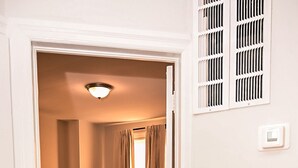 Habitación de hotel con dos camas, suelo de madera, una lámpara en el techo y una ventana con cortinas.