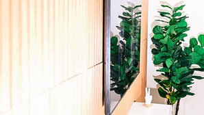 Una habitación moderna con un panel de madera en la pared, una mesa consola blanca, un espejo grande y una planta en maceta.