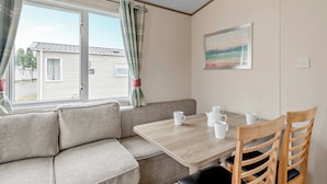 A room with a sofa, a table, and chairs. - Bronze 2 Bedroom Caravan, Sleeps 6. With parking (Great Yarmouth)
