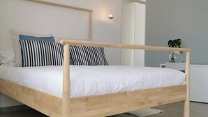 A modern bedroom with a wooden bed frame, white bedding, and a small bedside table with a plant. - Breeze Suite with large terrace - Villa Maria (Sperlonga)
