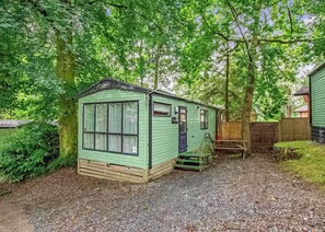 A small, single-story, green mobile home with a front porch, a window, and a door. - Bronze Premium 1 Bedroom Caravan, Sleeps 2 (Great Yarmouth)