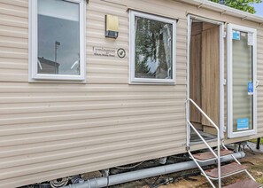 Ein Wohnmobil mit Schiebetür, einem Fenster und einer kleinen Außenterasse mit Stufen.