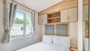 Una camera da letto con un letto, una finestra con tende, una testiera in legno e armadi a muro.