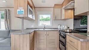 Una cucina compatta con mobili in legno, un fornello, un lavello e una finestra che fa luce naturale.