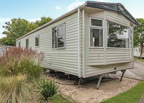 Ein Mobilheim mit Bungalow-Bauweise, einer einladenden Veranda und einer kleinen angeschlossenen Garage.