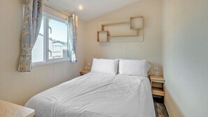 Una camera da letto con un letto, tende, un comodino e una mensola a muro.