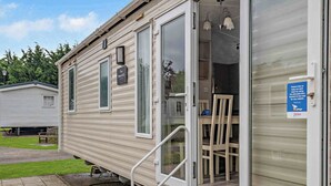 Un'abitazione mobile con porta scorrevole, un piccolo portico e un cartello che richiede lo smaltimento dei rifiuti.
