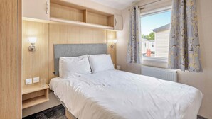 Una camera da letto con un letto, lampade sui comodini, una finestra con tende e scaffali a muro.