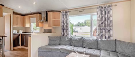 Una cocina moderna con armarios de madera, horno integrado y ventana con vistas a una zona residencial.