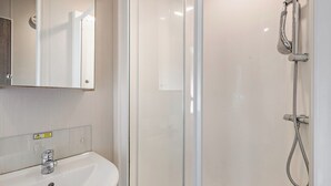 A modern bathroom with a glass shower enclosure, a sink, and a mirror. - Silver Caravan with parking (Great Yarmouth)