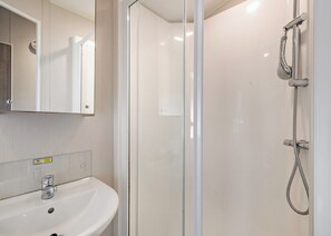 A modern bathroom with a glass shower enclosure, a sink, and a mirror. - Silver Caravan with parking (Great Yarmouth)