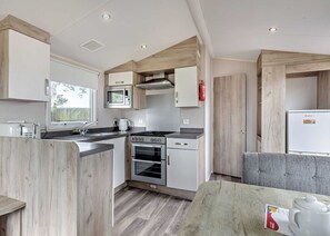 A compact kitchen with a microwave, stove, oven, and a small refrigerator. - Silver Caravan with parking (Great Yarmouth)