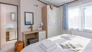 Ett hotellrum med en säng, ett nattduksbord, en spegel och ett fönster med gardiner.