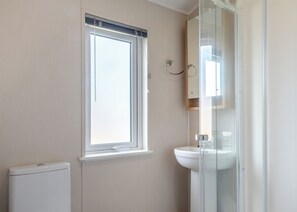 Un baño con ventana, inodoro y cabina de ducha de vidrio.