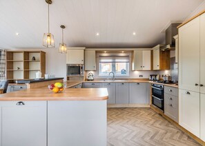 A modern kitchen with a central island, wooden cabinetry, and a herringbone floor pattern.