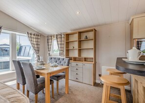A dining area with a table set for four, a bar stool, and a kitchen area with a counter and cabinets.