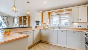 Una cocina moderna con armarios blancos, encimera de madera y un suelo con patrón de espiga.