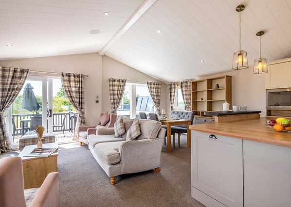 A spacious living area with a sofa, a dining table, and a kitchen area with a wooden countertop and cabinets.