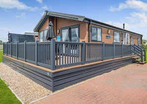 A mobile home with a deck, a covered patio, and a staircase leading to the entrance.