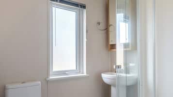 Un baño con ventana, inodoro y cabina de ducha de vidrio.