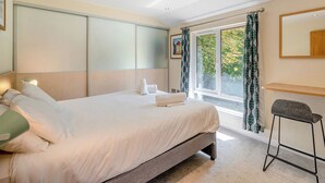 Een hotelkamer met een bed, een bureau, een stoel, een raam met gordijnen en een schilderij aan de muur.