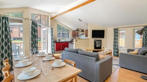 Een ruime woonkamer met een eettafel voor vier personen, een grijze bank en een keuken op de achtergrond.